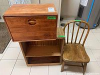 Wooden bread box with three drawers, small unfinished wood shelf, and vintage wooden kids chair in a tiled indoor setting.