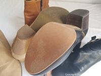 Close-up photo showing the soles and heels of the shoes highlighting minimal wear on cream-colored block heels and the sole of a black boot.