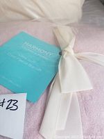 Close-up of the Harmony Home coral fleece blanket label tied with white ribbon showing the brand and new condition with tags.