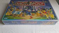 Sealed box of Disney Edition Monopoly board game featuring iconic Disney characters and bilingual labeling.