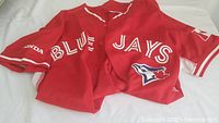 Front view of red Blue Jays shirt with printed front text and logo.