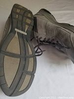 Side and tread view of one shoe showing grey suede and fabric upper with visible lacing and rubber sole tread.