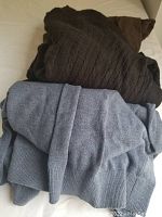 Folded brown cable knit sweater on top of a folded light blue sweater with a belt.