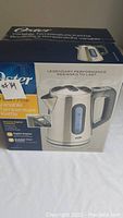 Box of Oster variable temperature kettle showing brand, capacity, and features.