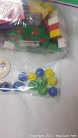 Plastic bags containing assorted Lego pieces, marbles, and a POG on a white surface