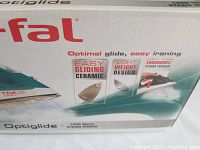 Box of T-fal Optiglide steam iron showing branding, features like easy gliding ceramic soleplate, ergonomic steam trigger, lightweight design.
