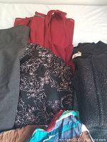 Assorted women's clothing including skirts, tops, and sweaters shown folded on a white background.