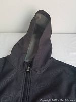 Photo of the jacket showing the hood and front zip with floral pattern on fabric.
