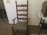 Full view of antique wooden rocking chair showing carved ladder back and frame