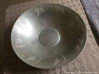 Top view of large metal bowl showing embossed leaf designs around the inside.