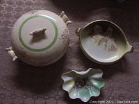 Photo showing three vintage ceramic dishes: covered bowl with lid, decorative bowl with cherubs, and scalloped soap dish.