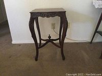 Front view of dark wooden corner table showing carved legs and overall shape