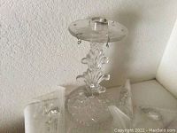 Full view of clear glass candle holder with decorative stem and base, hooks present for hanging glass prisms
