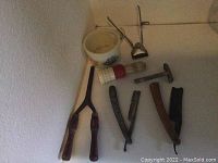 Photo of vintage grooming tools including manual hair clippers, two straight razors, a metal razor, shaving cream cup, and a shaving brush.