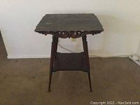 Photo showing full view of the old large corner table with tapered legs and scalloped edge top against a white wall.