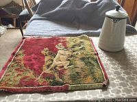 Coffee pot next to small dog-design rug on bed surface