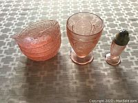 Photo showing four pink glass bowls stacked and pink glass salt shaker with metal top