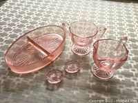 Overview of all pink glass items including serving dish, sugar bowl, creamer, and two small pieces.