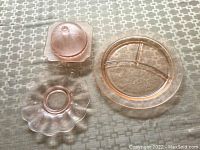 Four pink glass dishes arranged on a fabric background showing shape and size of each.