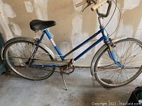 Blue retro CCM bicycle with horizontal step-through frame, black saddle, beige grips, metal fenders, and rust showing on various parts.
