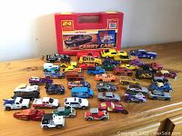 Photo showing full lot with 38 assorted Hot Wheels cars and one red carrying case in background