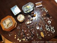 Overview of the lot showing jewelry boxes, perfume bottles, necklaces, earrings, pins, and cufflinks on a wooden surface.