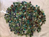 Top view of large assortment of glass marbles of various colors spread on a white cloth.