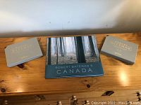 Two grey slipcases and one hardcover book “Robert Bateman’s Canada” on wood surface