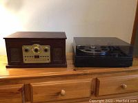 Sylvania radio console and Realistic turntable placed side by side on wooden surface.