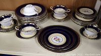 Overview of full set arranged on shelf showing plates, bowls, cups and saucers.
