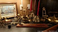 Brass candle holders with candles, brass figurines including an owl, small brass items, the framed print in the background