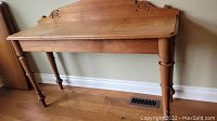 Front-facing view of the wood console table showing backsplash and tapered legs