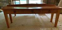 Front view showing full length of pine console table with three drawers and raised back edge.