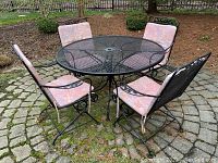 Set of round metal mesh table and four chairs with cushions on patio