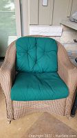 Front view of wicker rocker with green cushions
