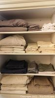 Folded king size sheets and pillowcases arranged on shelves showing various colors and sizes.
