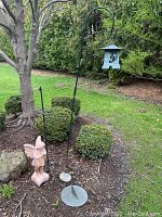 Full view showing tall shepherd's hook, concrete angel, butterfly rock, and sundial base