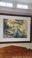 Full view of the framed watercolor painting hung on wall, showing irises and lily pads at a pond with light reflections and surrounding greenery.