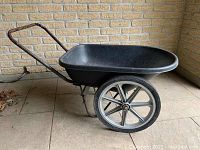 Side view of fibreglass wheelbarrow showing bucket, metal frame and two large never-go-flat wheels.