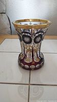 Front and side view of the vase showing ruby red color, clear cut details, and gold accents.