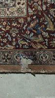 Close-up image showing the worn and damaged area of the rug along the edge with visible fiber loss and discoloration.