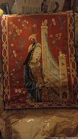 Full view of fabric banner depicting a medieval lady playing a harp, red floral background and geometric border