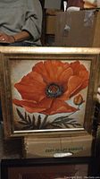 Front view of the painting showing the main orange Oriental poppy flower with green leaves and a smaller bud, framed in a gold-painted wooden frame.