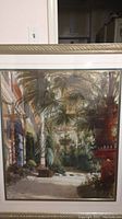 Front view of framed palm tree wall art showing a detailed indoor garden scene with palms and a veranda under natural light.
