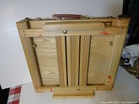 Back view of the wooden easel showing the folding mechanism and carrying handle.