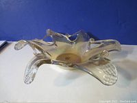 Side angle view of transparent Murano glass star-shaped bowl showing pierced openings and sculpted points.