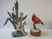 Pair of brass ducks in flight sculpture next to resting cardinal figurine