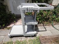 Side view of Rubbermaid janitorial cart showing shelves, compartments, and wheels