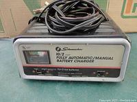 Front view of Schumacher battery charger showing display, control switches, and attached cables.