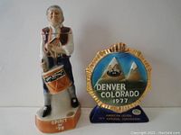 Full view of the two commemorative decanters showing the colonial drummer figure and round medal-shaped decanter.